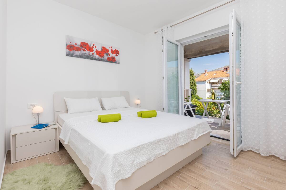 A bedroom with a bed, nightstand, and a view of the outside.
