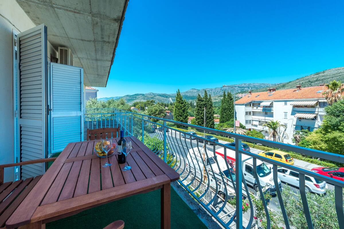 A balcony with a wooden table, a chair, and a wine glass.