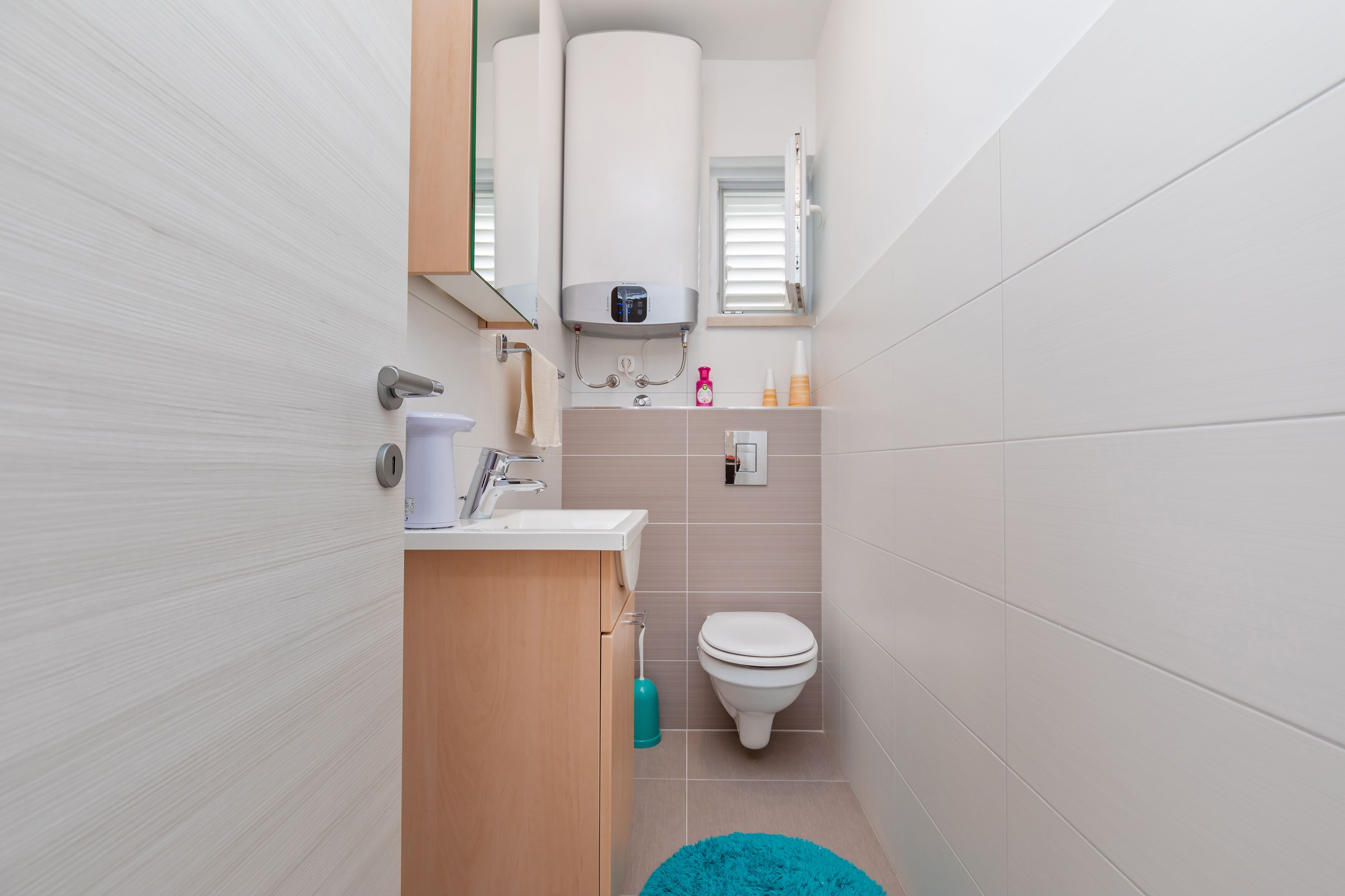 A compact bathroom with a toilet, sink, and a towel rack.