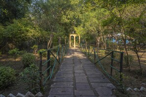 A stone pathway leading to a gazebo in a wooded area. - Maharaja Kothi (Manpur)