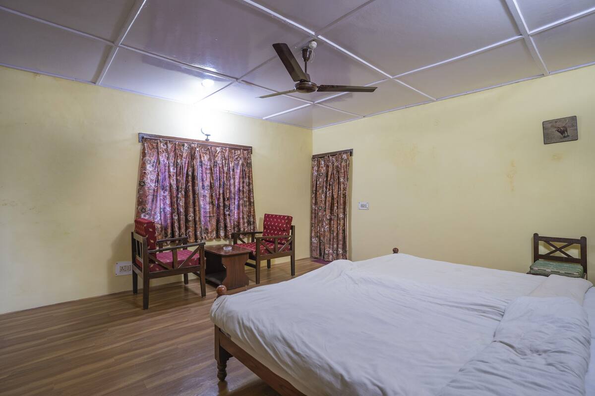 Un dormitorio con cama, una silla, un escritorio y cortinas.