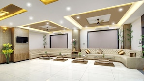 A spacious living area with a large beige sofa, multiple coffee tables, and a flat-screen TV mounted on the wall. - Trulyy Rudransh inn (Jodhpur)
