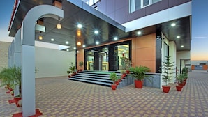 A modern building with a tiled entrance, steps leading to the door, and potted plants around the area. - Trulyy Rudransh inn (Jodhpur)