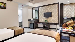 A hotel room with two beds, a desk, a TV, and a mirror. - Trulyy Rudransh inn (Jodhpur)
