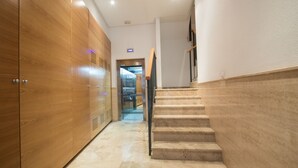 Un pasillo moderno con un armario de madera, una escalera y una pantalla digital en la pared.