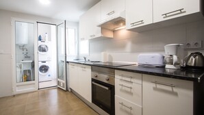 Una cocina moderna con armarios blancos, horno empotrado, tostadora y cafetera.