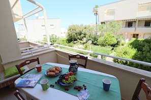 A balcony with a table set for breakfast, including croissants, fruit, and a pitcher.