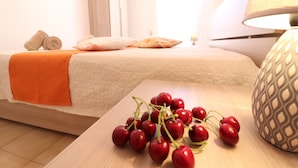 A hotel room with a bed, a bedside table with a lamp, and a table with cherries. - In Good Location And With Balcony - Casa Vacanze Nicole In Salento (Otranto)