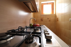 A kitchen with a gas stove, a window, and a tiled backsplash.