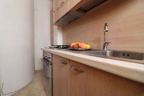 Eine Küche mit Spüle aus Edelstahl, Holzschränken und einer Arbeitsplatte mit Früchten.