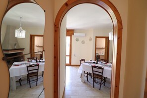 A dining area with a white tablecloth, wooden chairs, and a chandelier.