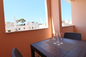 A dining area with a table and chairs, a view of buildings and a tree through a window.