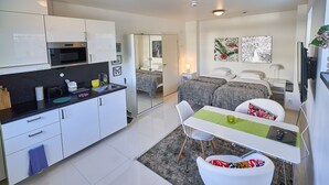 A modern kitchen with white cabinets, a microwave, and a dining area with a table and chairs. - Staylong Hotel (Taby)