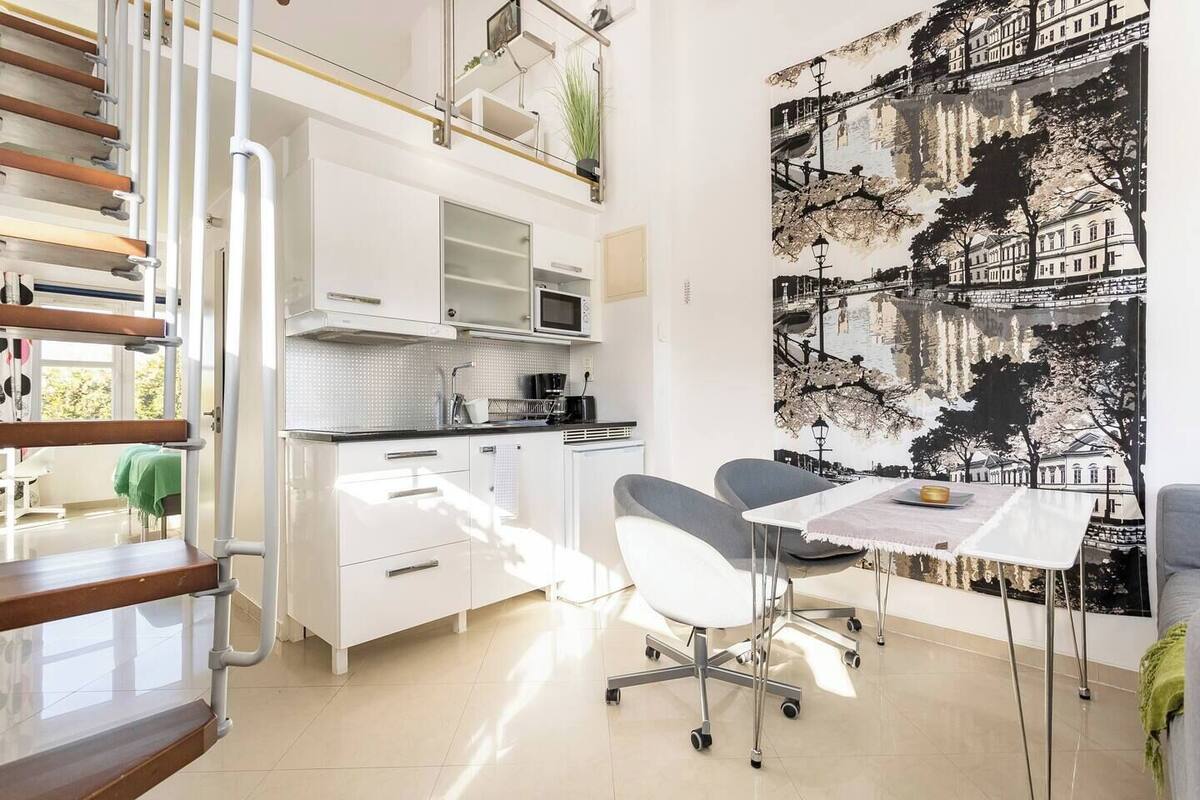 A modern kitchen with white cabinets, a microwave, and a dining area with a table and chairs.