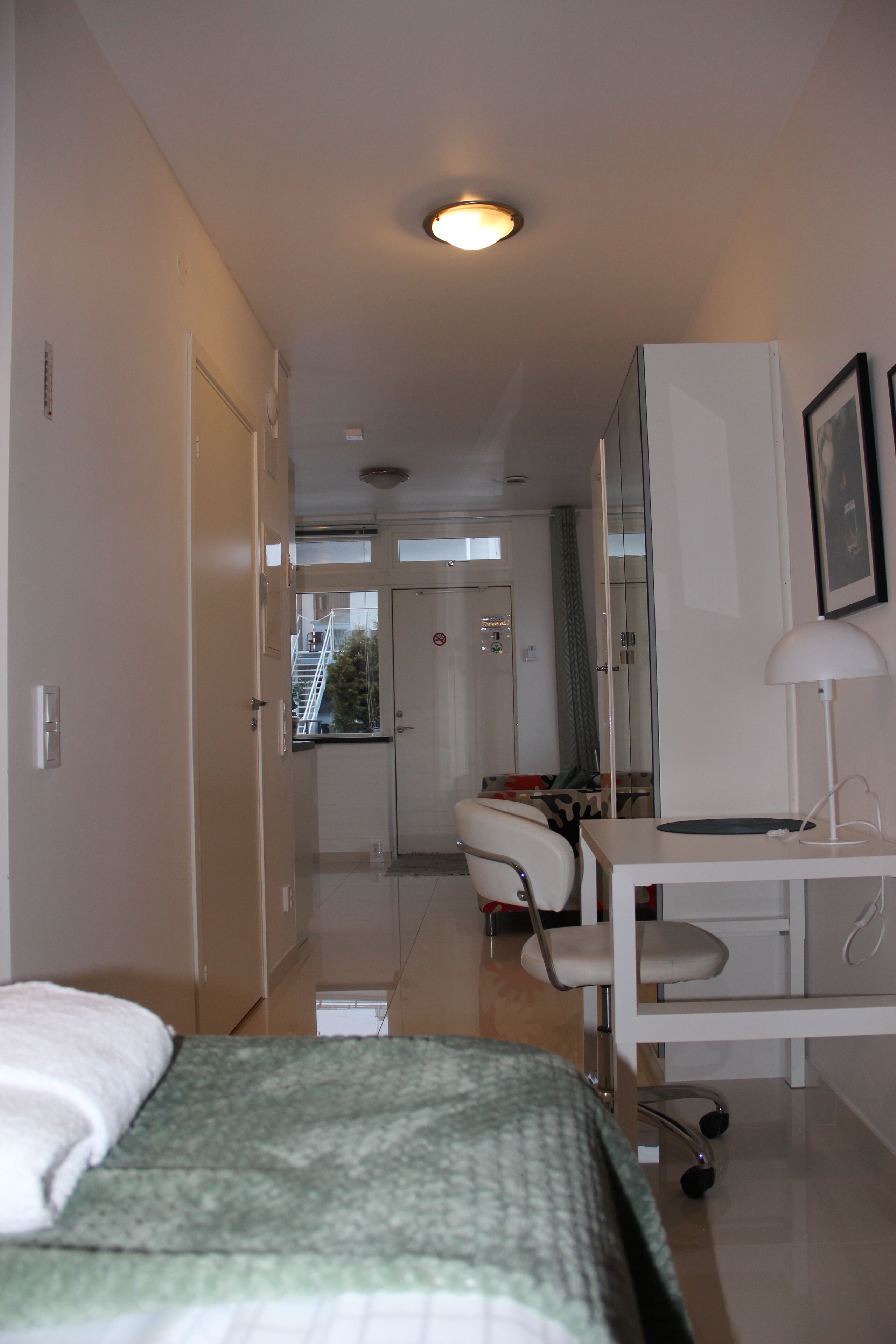 Habitación de hotel con cama, escritorio, silla, espejo y puerta que da a un baño.