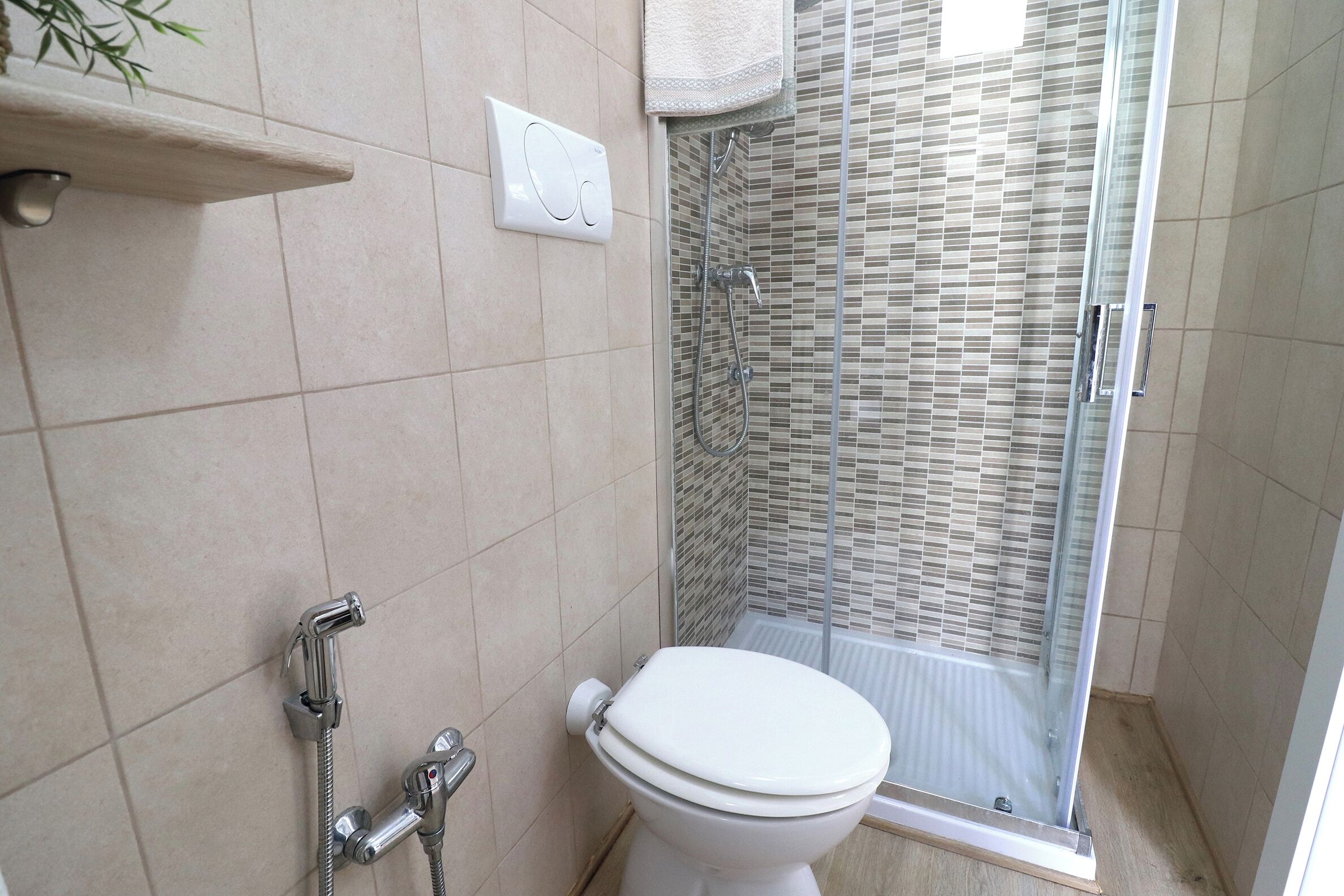 A bathroom with a toilet, shower, and a towel rack.