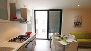 A modern kitchen with a gas stove, white cabinets, and a dining area with a table set for two.