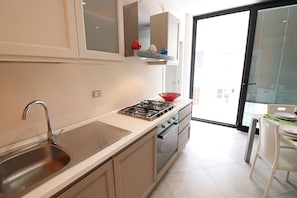 A kitchen with a stainless steel sink, a gas stove, and a window with a view of the outside.
