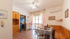 A cozy kitchen with wooden cabinets, a dining table with a floral tablecloth, and a ceiling fan.
