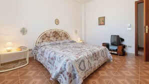 A bedroom with a bed, bedside tables, a television, and a door.