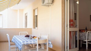 A dining area with a table set for two, a ceiling fan, and a sliding glass door leading to a balcony.