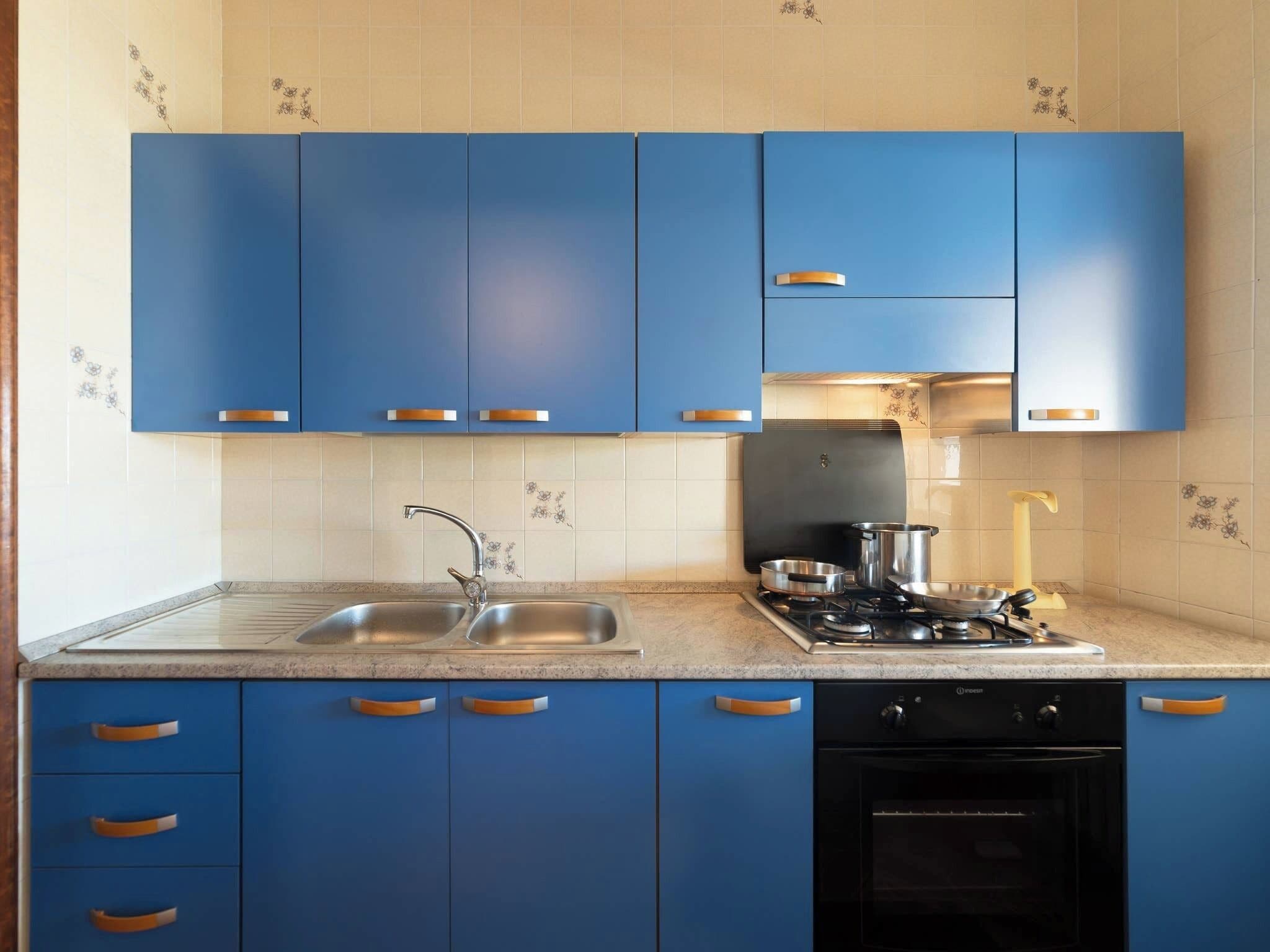 A modern kitchen with blue cabinets, a stainless steel sink, a gas stove, and a dishwasher.