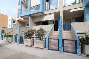 A multi-story residential building with a tiled exterior, a gated entrance, and a staircase leading to the entrance.