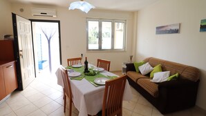 Un comedor con una mesa dispuesta para cuatro, un sofá y una ventana con vistas a zonas verdes.