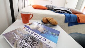 Una cama con almohadas, un plato con cruasanes, una taza y una revista sobre una mesa.