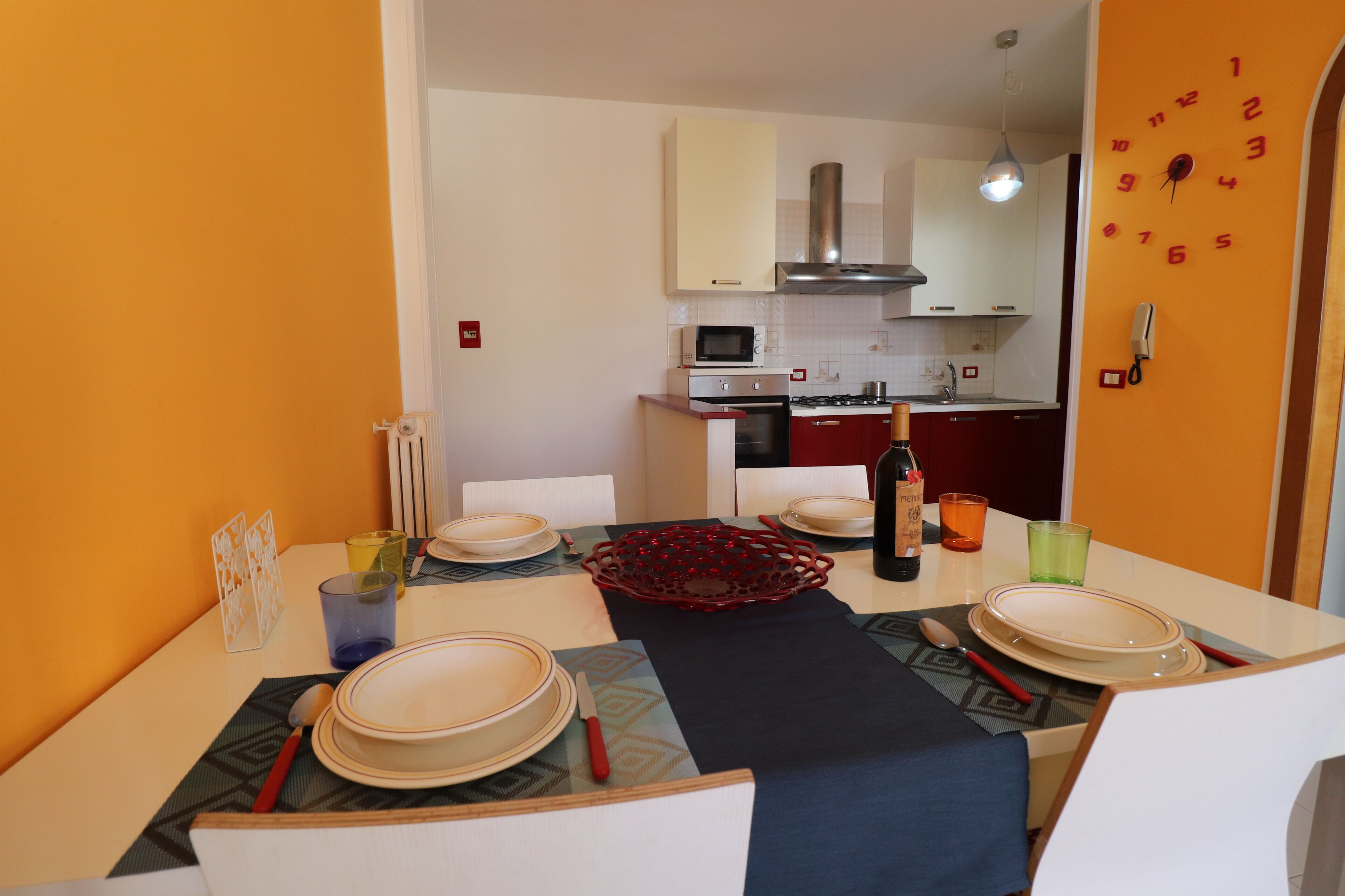 A dining area with a table set for four, a microwave, oven, and a stove in the background.