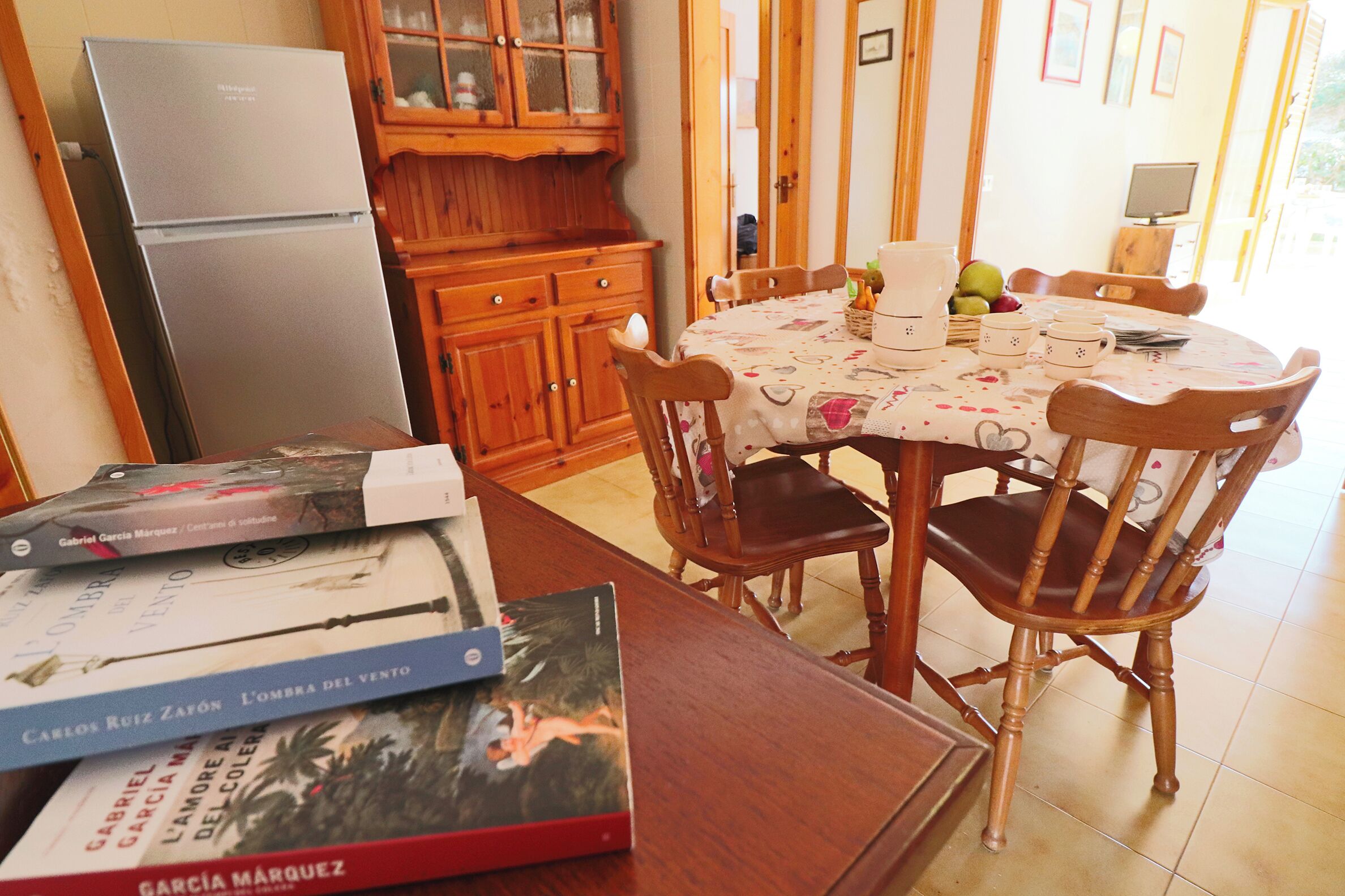 Ein Essbereich mit Holztisch, Stühlen und einem Kühlschrank im Hintergrund.