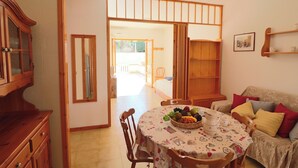 A dining area with a table set for two, a wooden cabinet, and a sofa with cushions. - Nice House Cecilia in Otranto (Otranto)