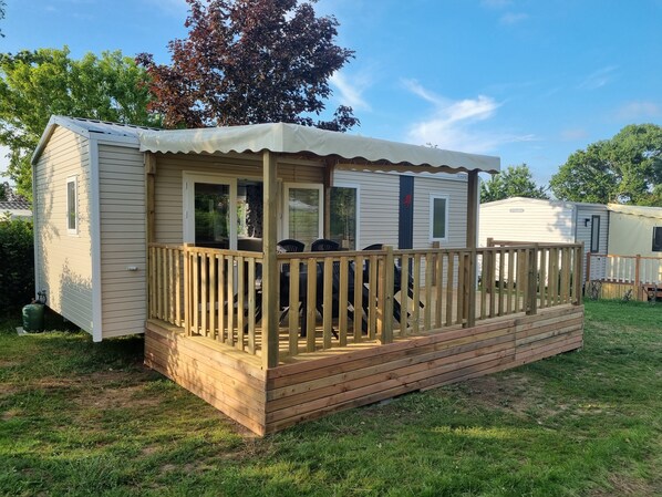 Uma casa móvel com um deck de madeira e varanda coberta.