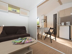 Um espaço compacto com sofá, mesa com revistas, cozinha compacta e área de jantar.