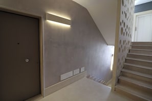 A staircase with a modern design, a door with a handle, and a wall with a light strip.