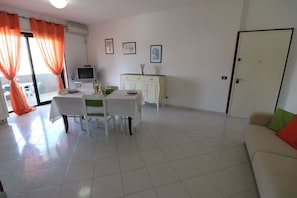 A dining area with a table, chairs, and a television on a cabinet.
