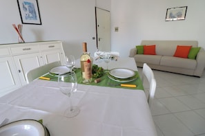 A dining table set with plates, glasses, a bottle, and a corkscrew.