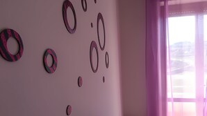 Ein Zimmer mit einer Wand, die mit kreisförmigen Mustern verziert ist, und einem Fenster mit durchsichtigen Vorhängen.