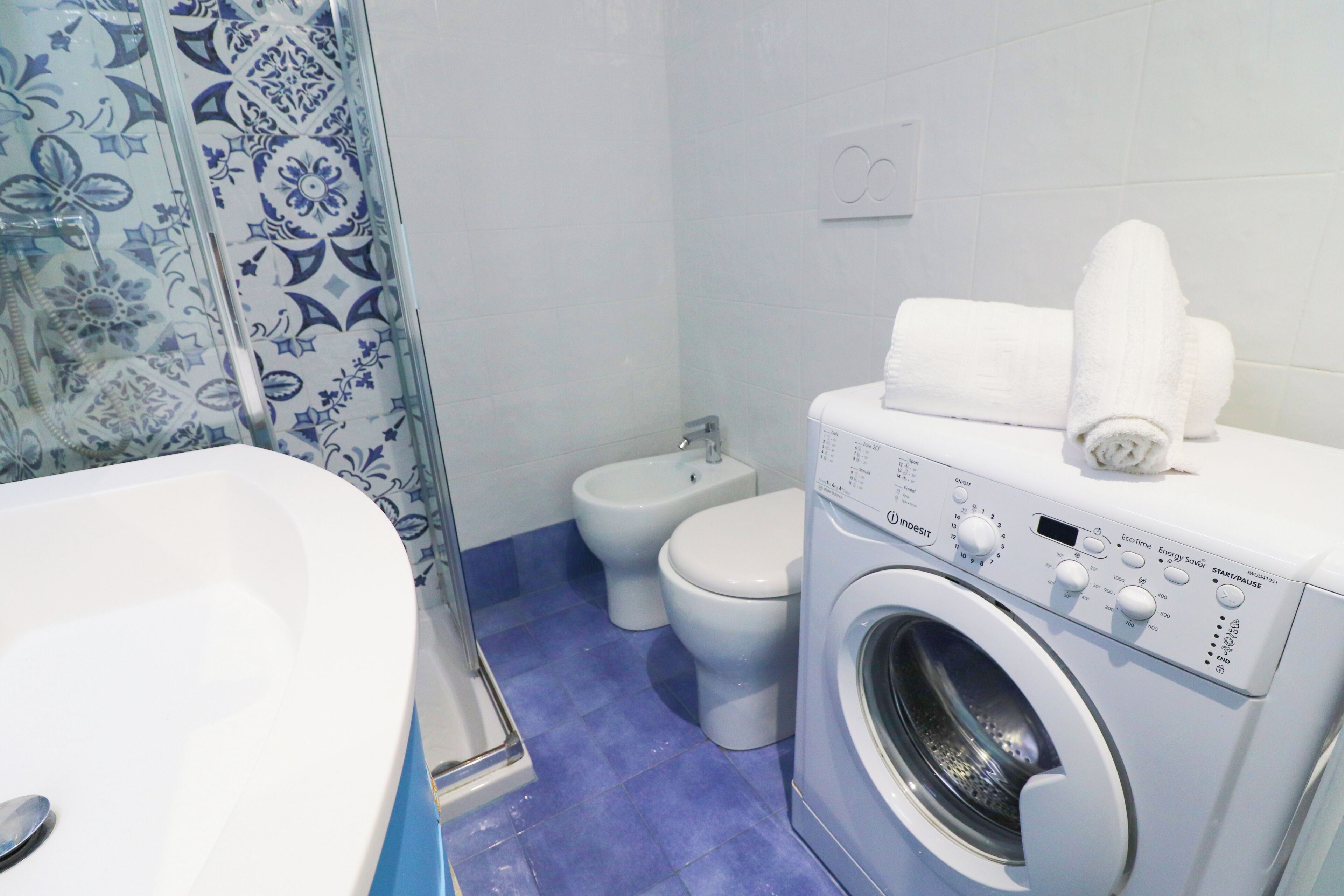 A bathroom with a washing machine, a bidet, and a bathtub.