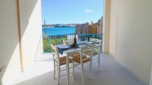 A balcony with a table set for two, overlooking a coastal view with a clear sky. - Casa Lucrezia Unique Sea View and Relaxation Near the Historic Centre (Otranto)
