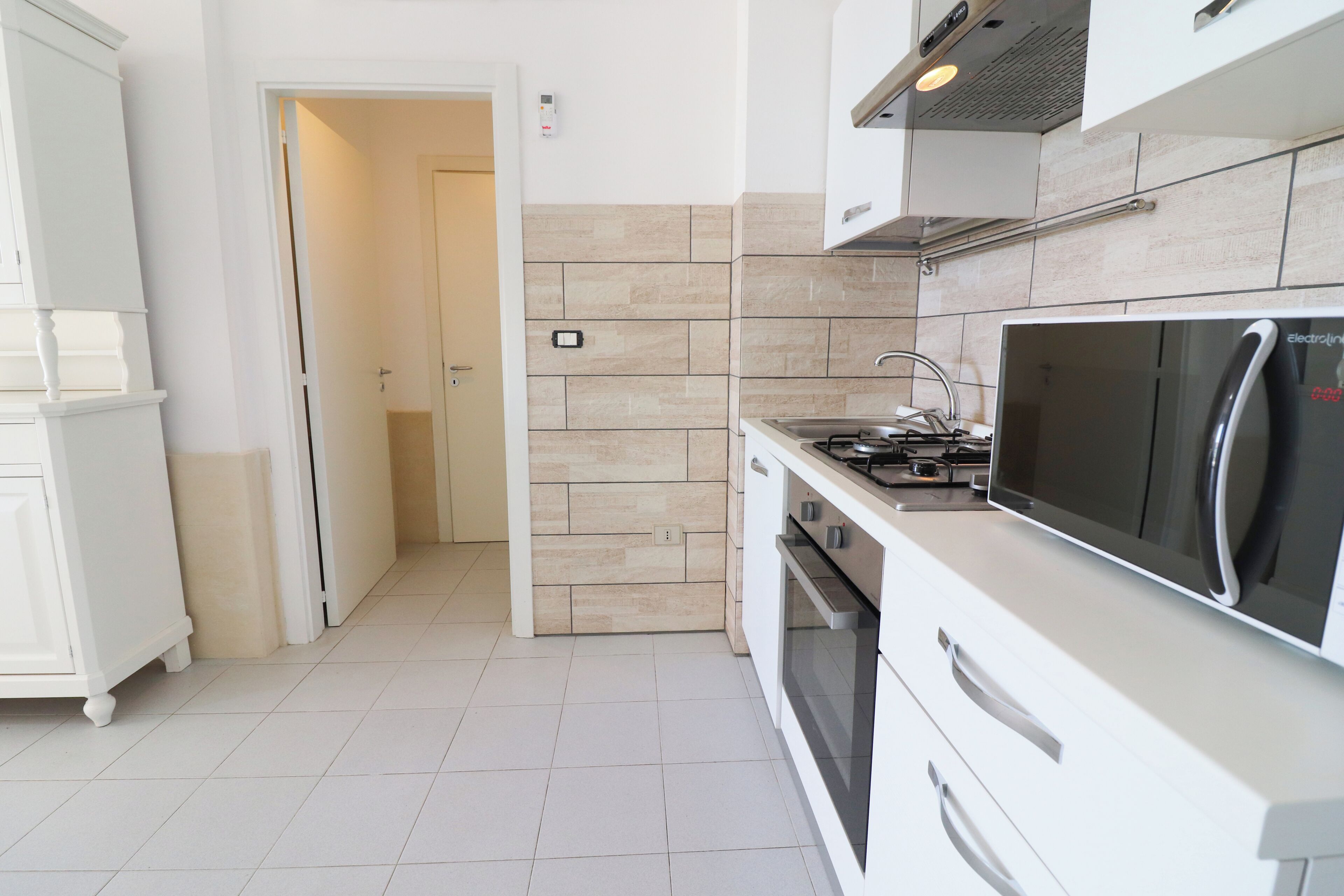 A modern kitchen with white cabinetry, a microwave, and an oven.