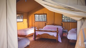A cozy room with two single beds and a larger bed, wooden flooring, and a window with curtains. - Canvas & Clover (Worcester)