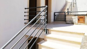 A staircase with metal railings leading to a door, a small outdoor area with steps, and a building with a white exterior. - Holiday Home Barbara (Otranto)