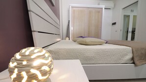 A bedroom with a bed, a bedside table, and a wall-mounted lamp. - Modern Apartment "casa Giuditta Deluxe A Otranto" (Otranto)