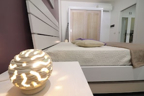 A bedroom with a bed, bedside table, and a decorative lamp. - Modern Apartment "casa Giuditta Deluxe A Otranto" (Otranto)