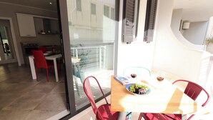 A dining area with a table, chairs, and a view of the kitchen and balcony. - Modern Apartment "casa Giuditta Deluxe A Otranto" (Otranto)