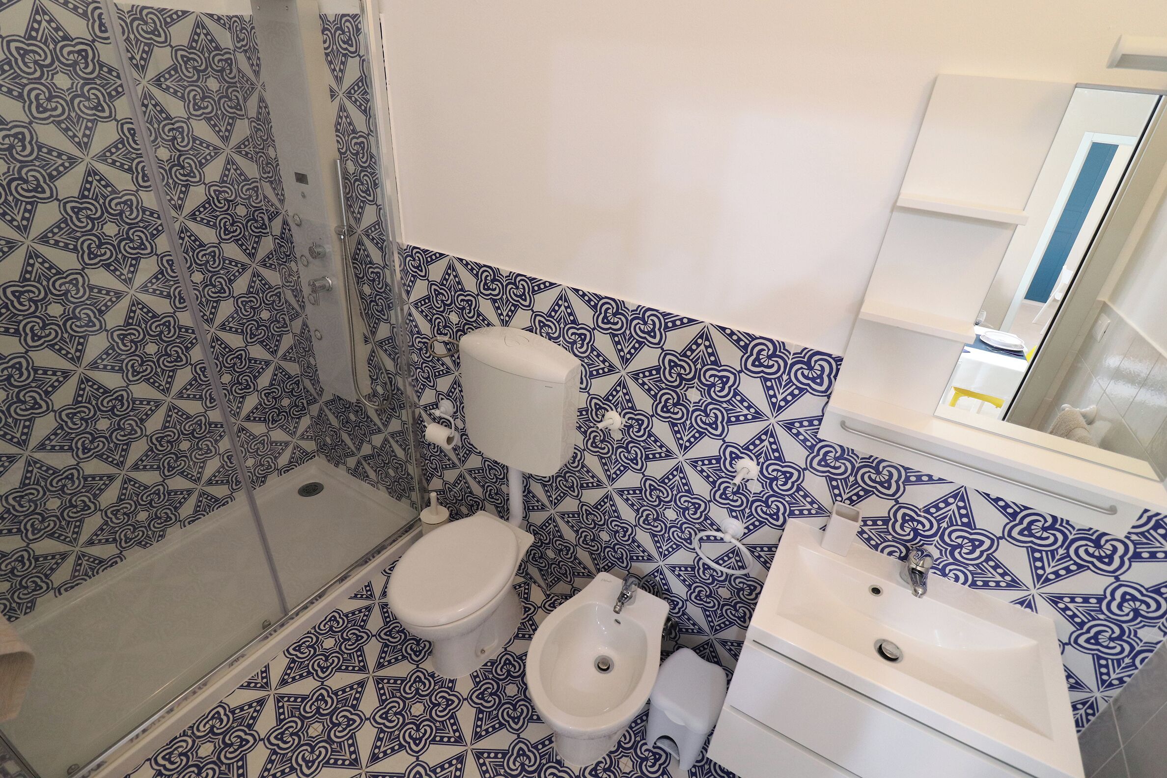 A bathroom with a shower, toilet, bidet, and sink.