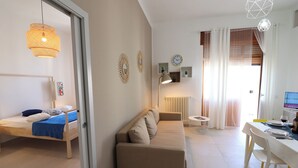 A modern living room with a sofa, a bed, a dining table, and a computer.