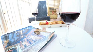 A table with a glass of red wine, a brochure, and a tray of pastries.