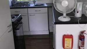A compact kitchen with white cabinets, a gas stove, a sink, and a window. - 2 Bedroom Chalet Near the Beach (Sandown)